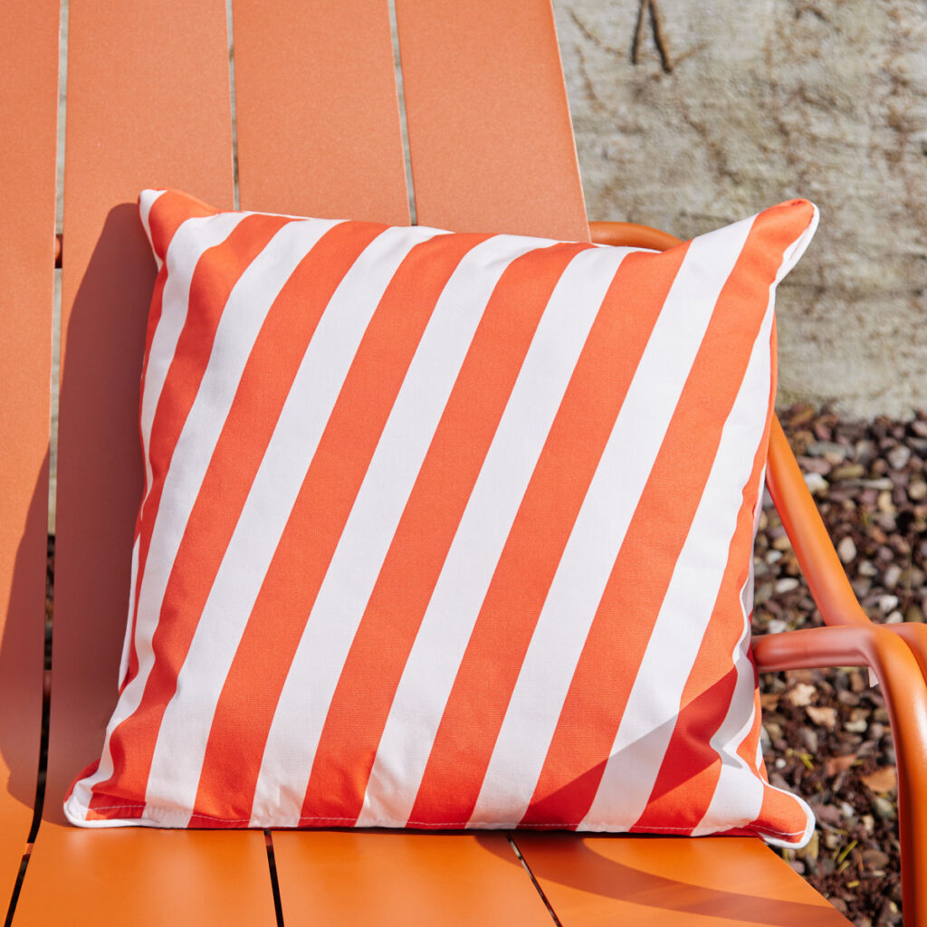 weather-resistant outdoor cushion in orange and white with a stripe pattern